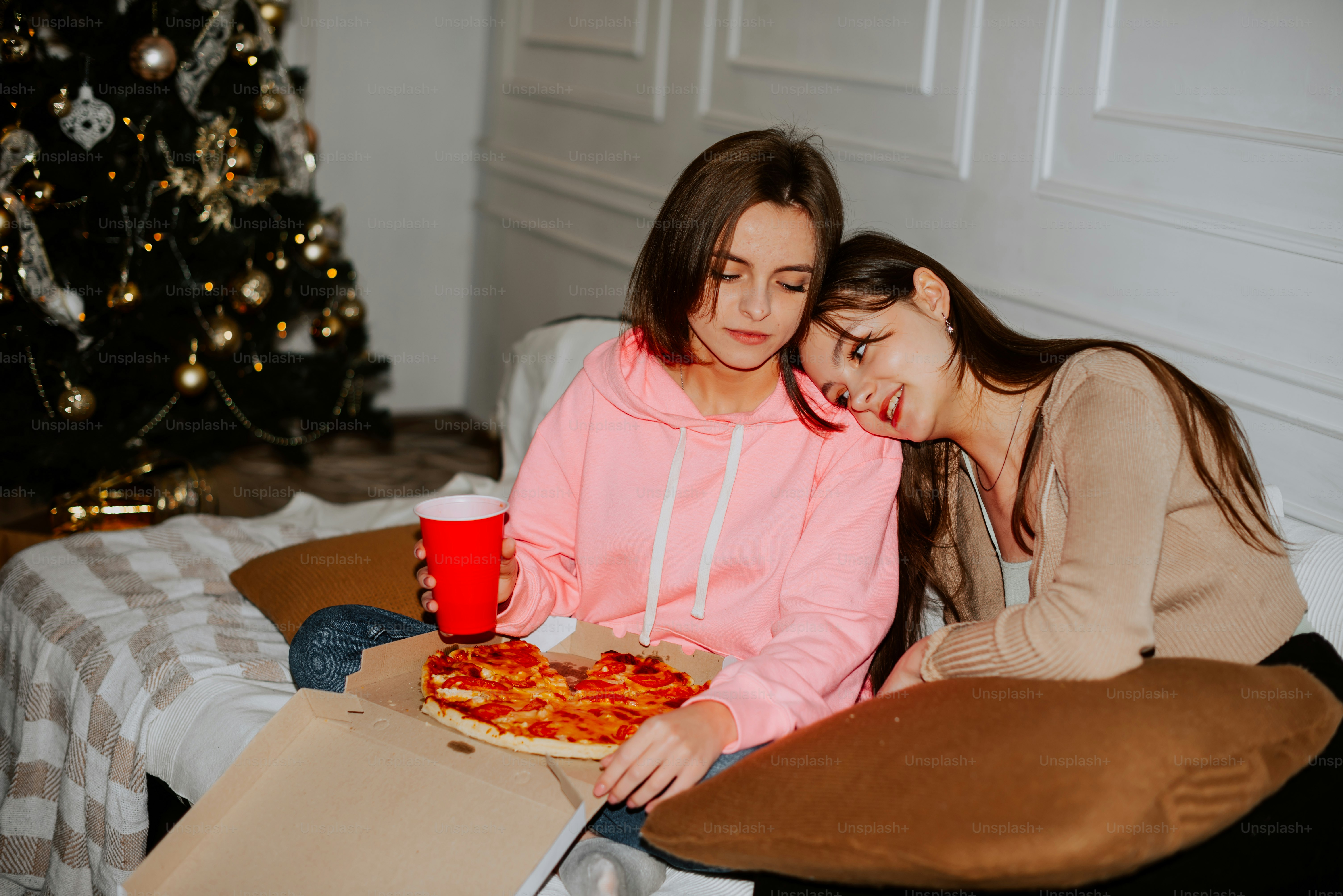 a couple of women sitting on top of a bed