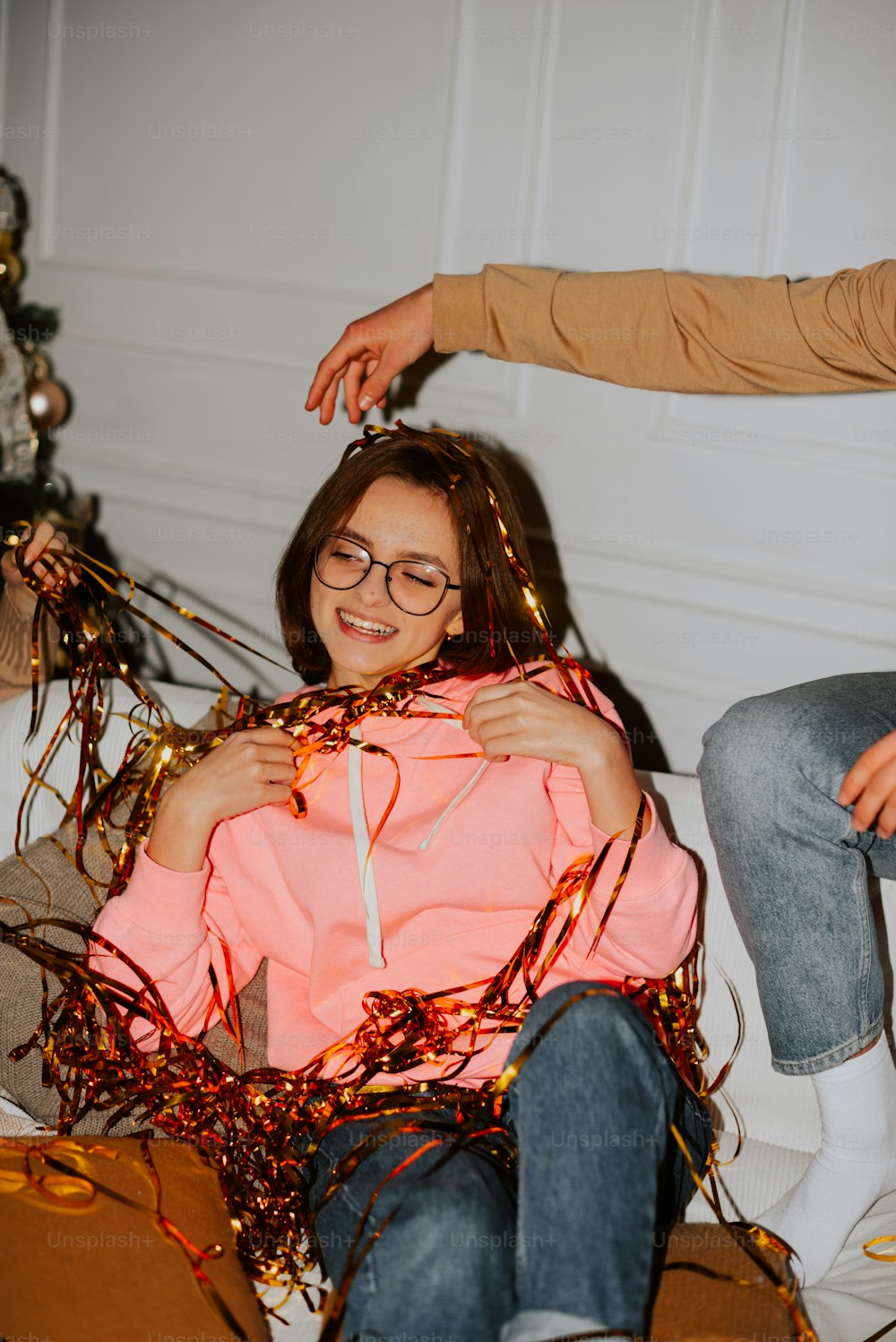 a woman sitting on a bed with a man helping her to tie her hair