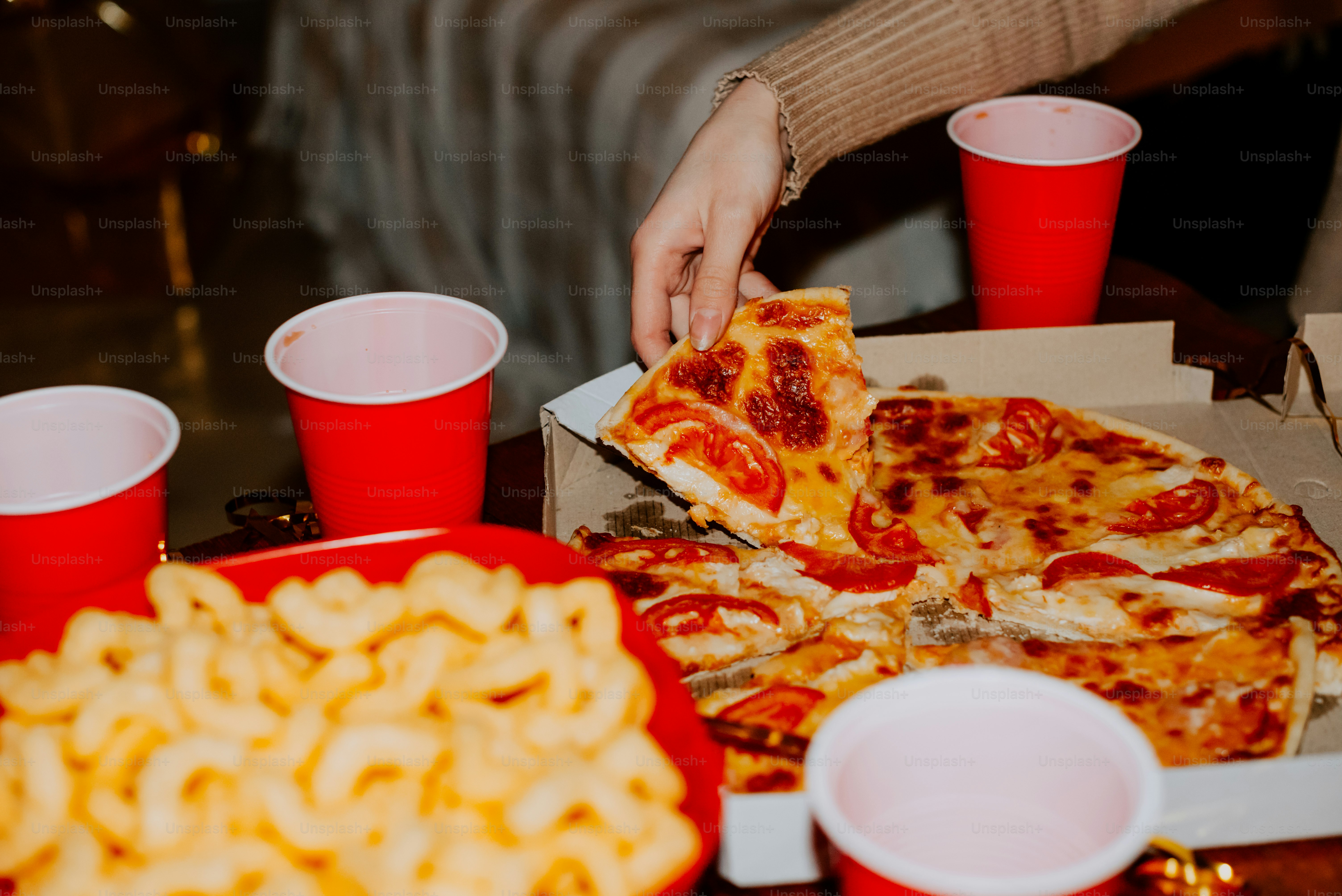 a person grabbing a slice of pizza from a box