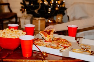 ein Tisch mit Pizza und Tassen gefüllt mit Getränken