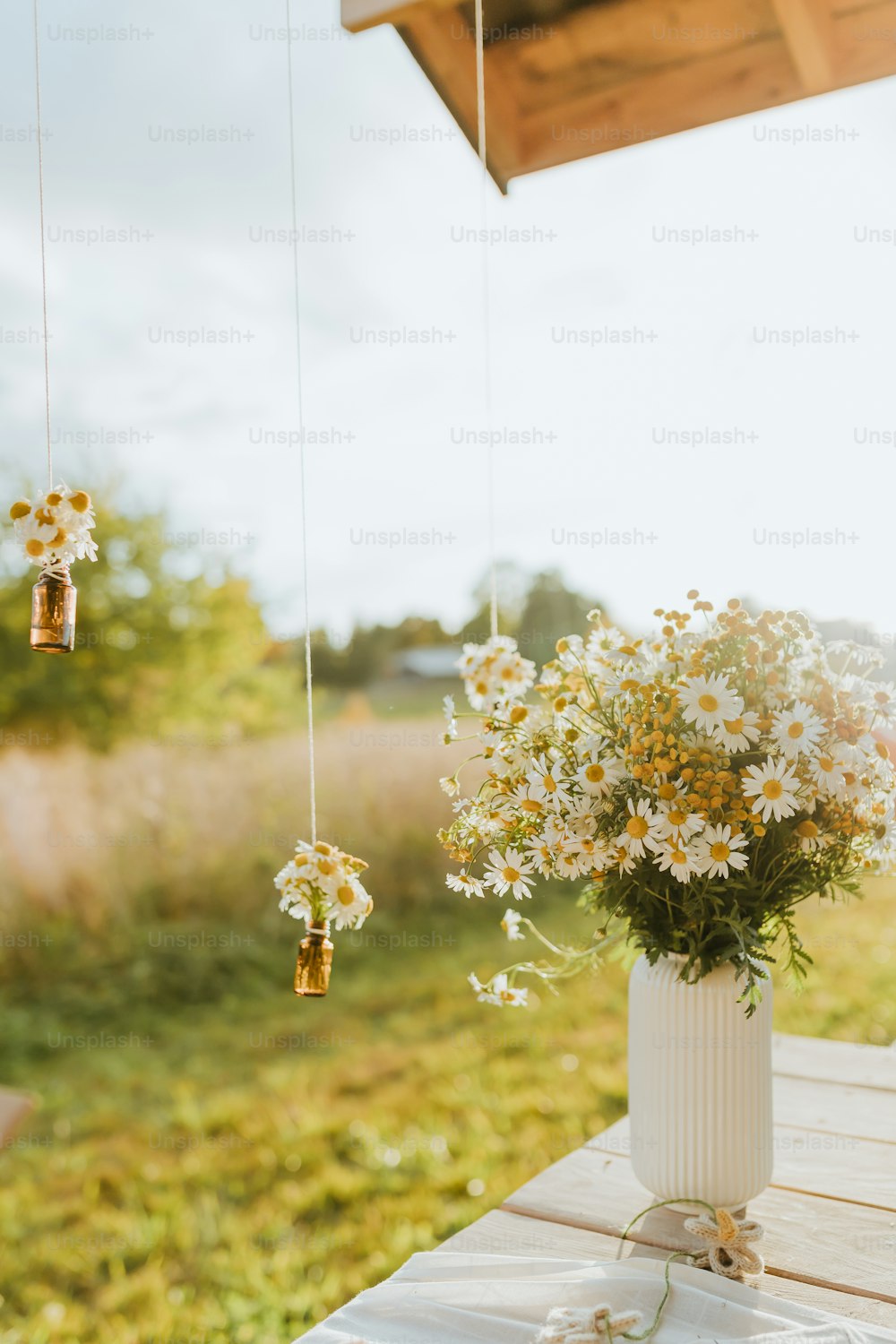 un vase blanc rempli de fleurs posé sur une table en bois