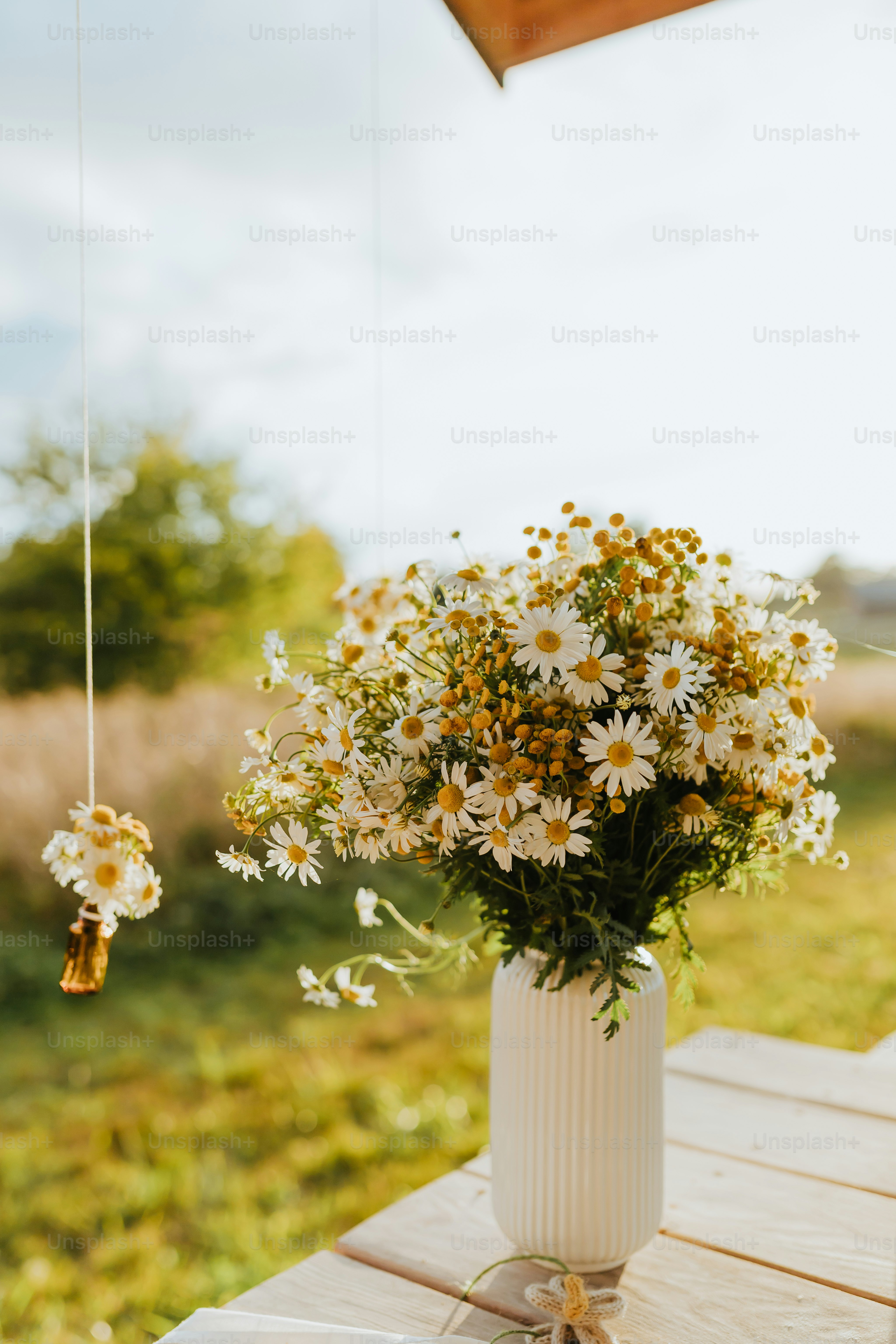 a white vase filled with lots of flowers on top of a wooden table