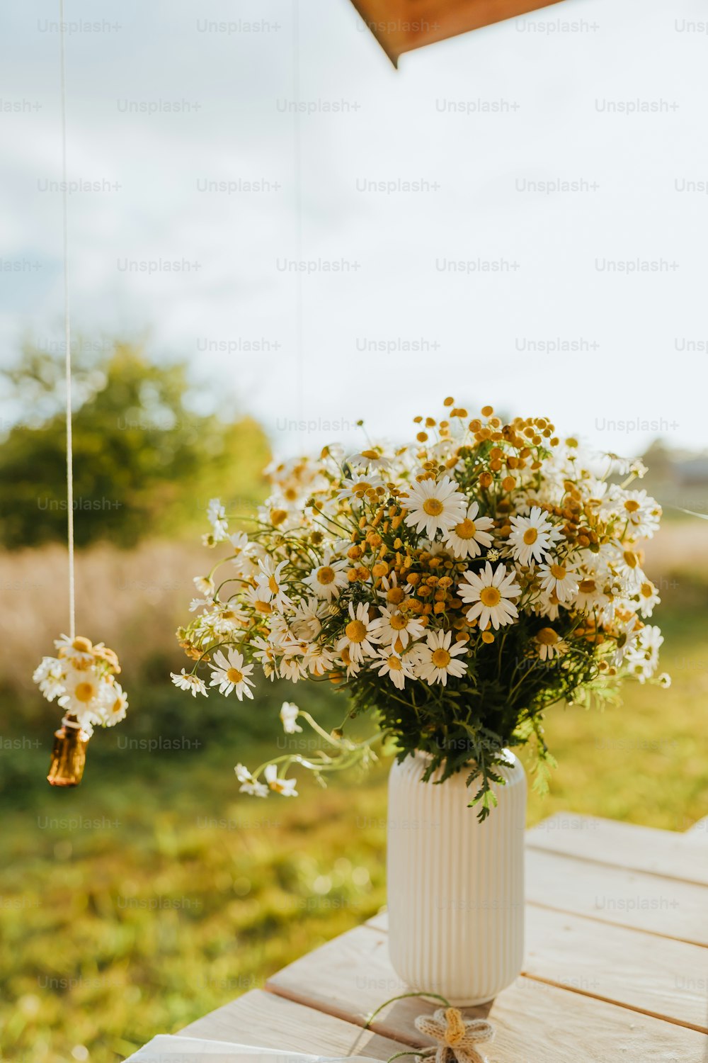 um vaso branco cheio de muitas flores em cima de uma mesa de madeira