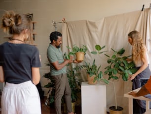 a couple of people that are looking at a potted plant