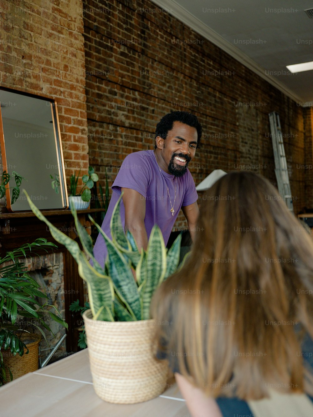 a man sitting at a table with a potted plant