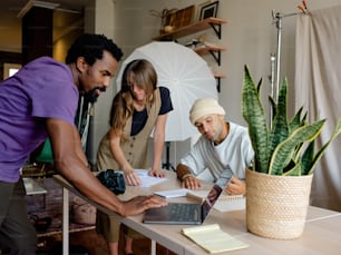 a group of people standing around a table with a laptop