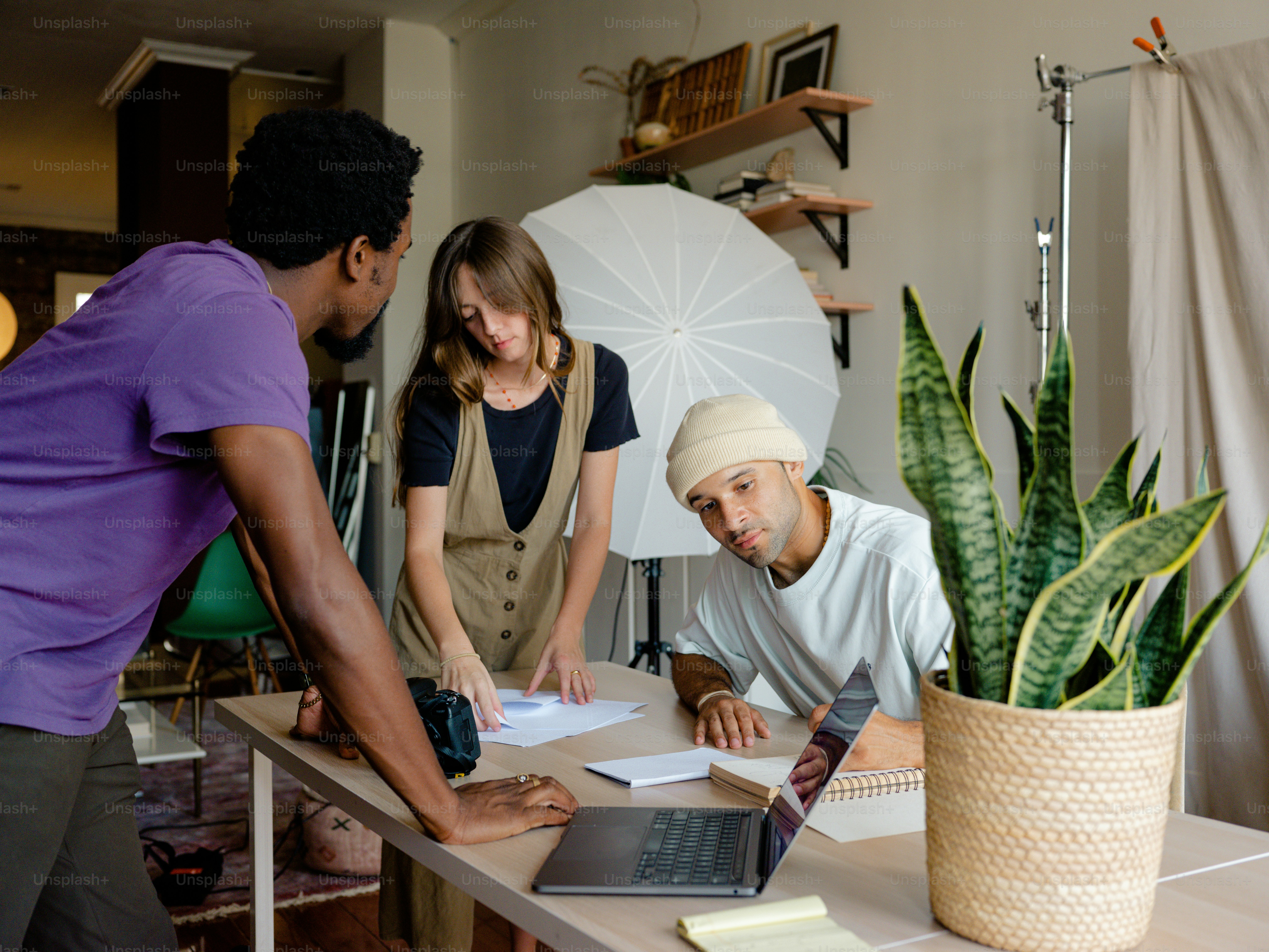 A group of people standing around a table with a laptop photo – Working ...