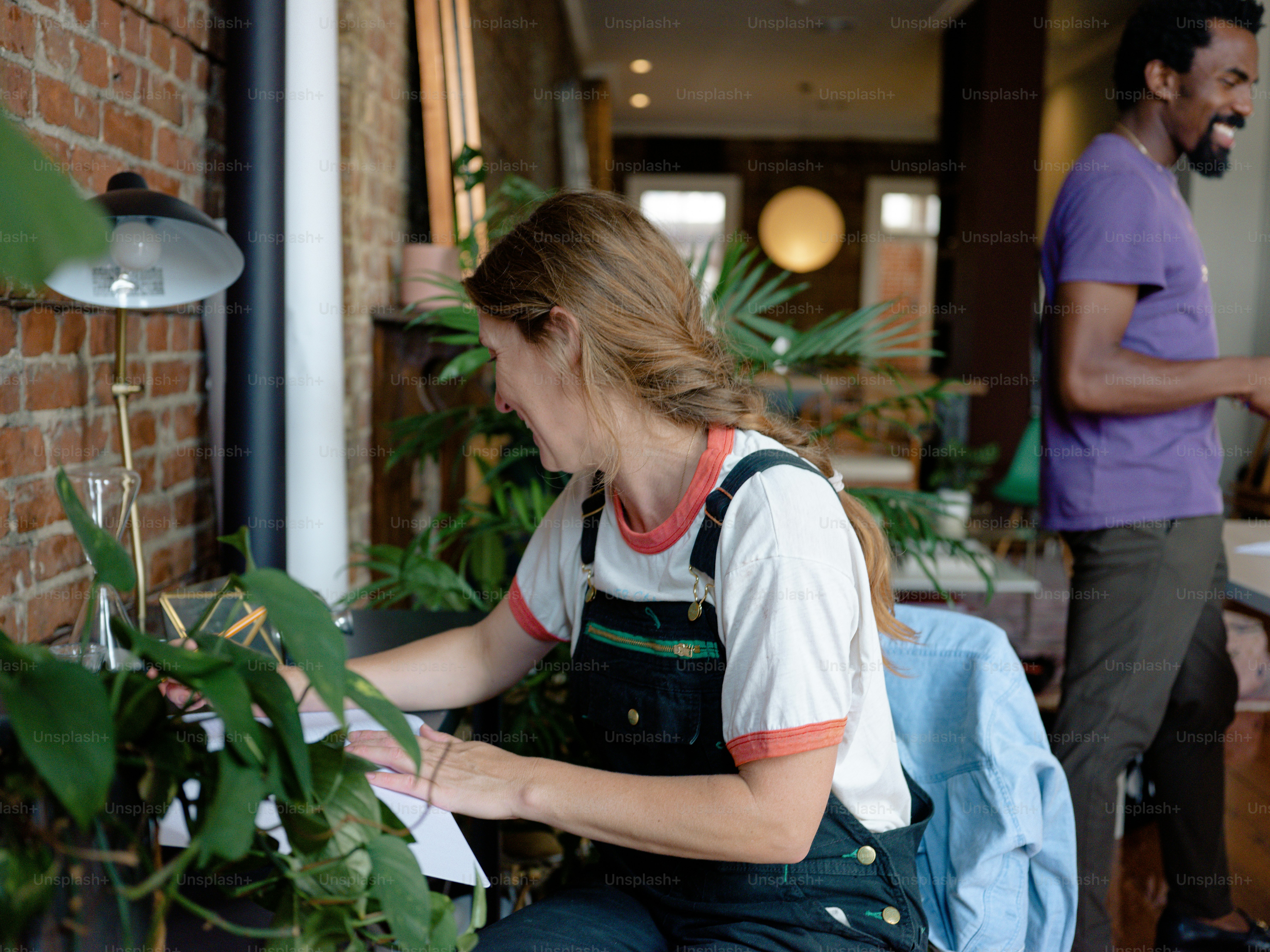 Une femme assise sur une chaise devant un mur de briques