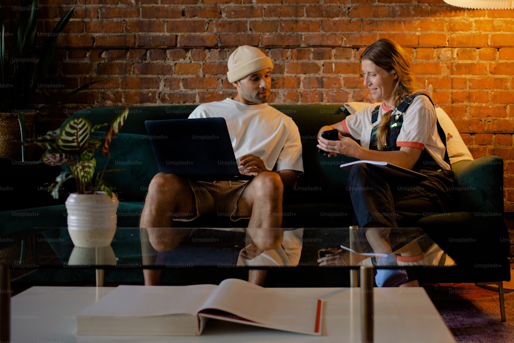 a man and a woman sitting on a couch using laptops