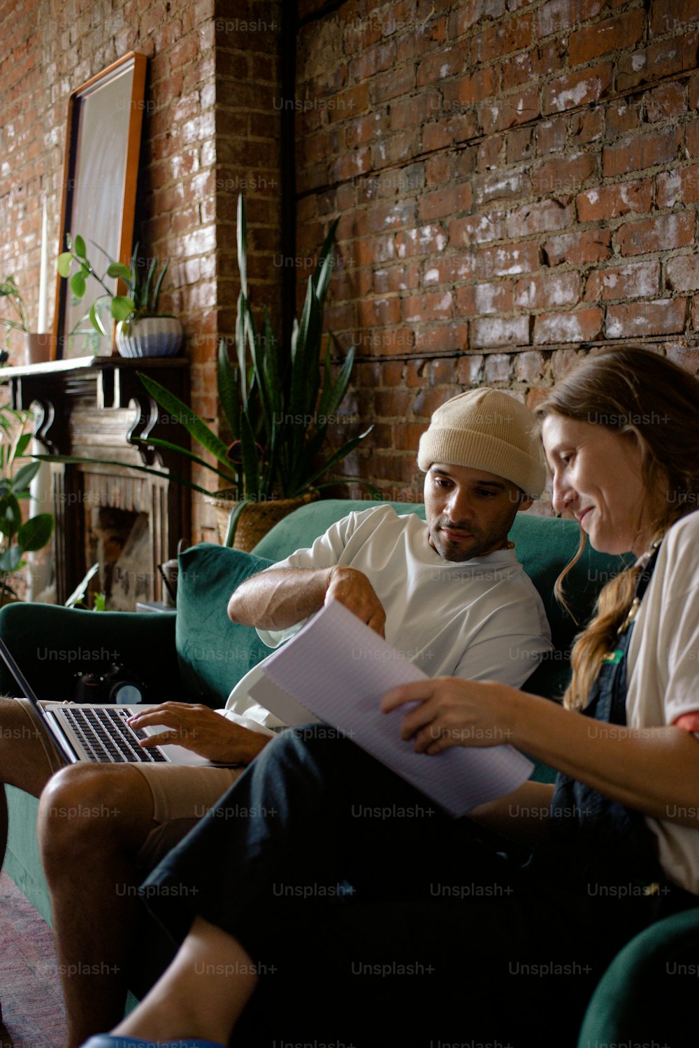 a man and a woman sitting on a couch with a laptop