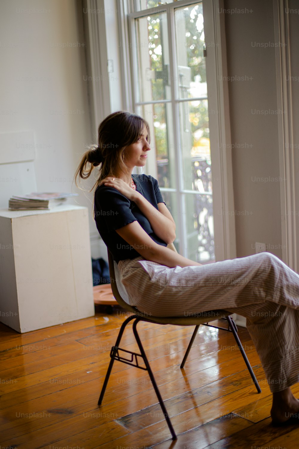 a woman sitting in a chair looking out a window