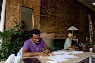 a man sitting at a table with a laptop and papers