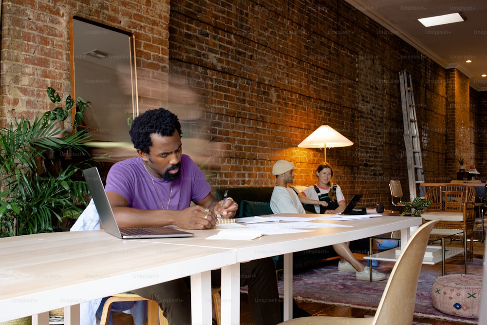 um homem sentado em uma mesa trabalhando em um laptop