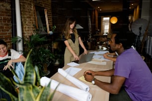 a group of people sitting at a table with laptops