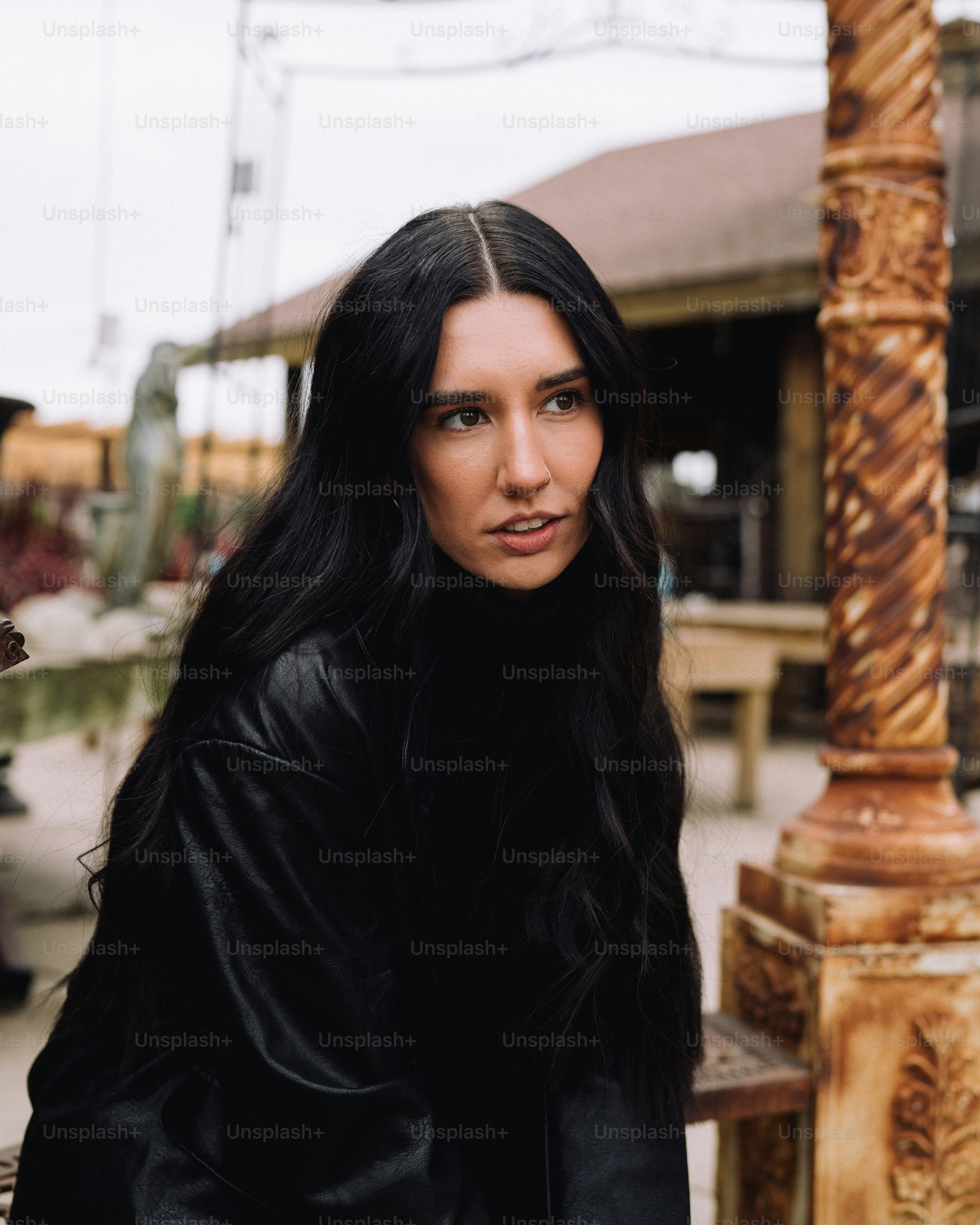 a woman with long black hair standing next to a pole