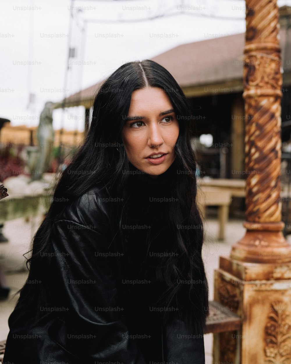 a woman with long black hair standing next to a pole