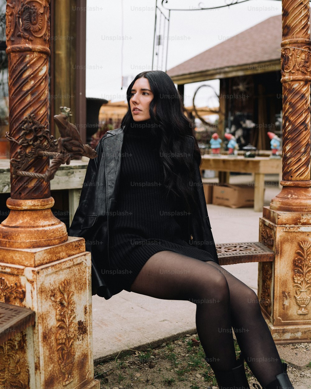 Eine Frau, die in einem schwarzen Kleid auf einer Holzbank sitzt