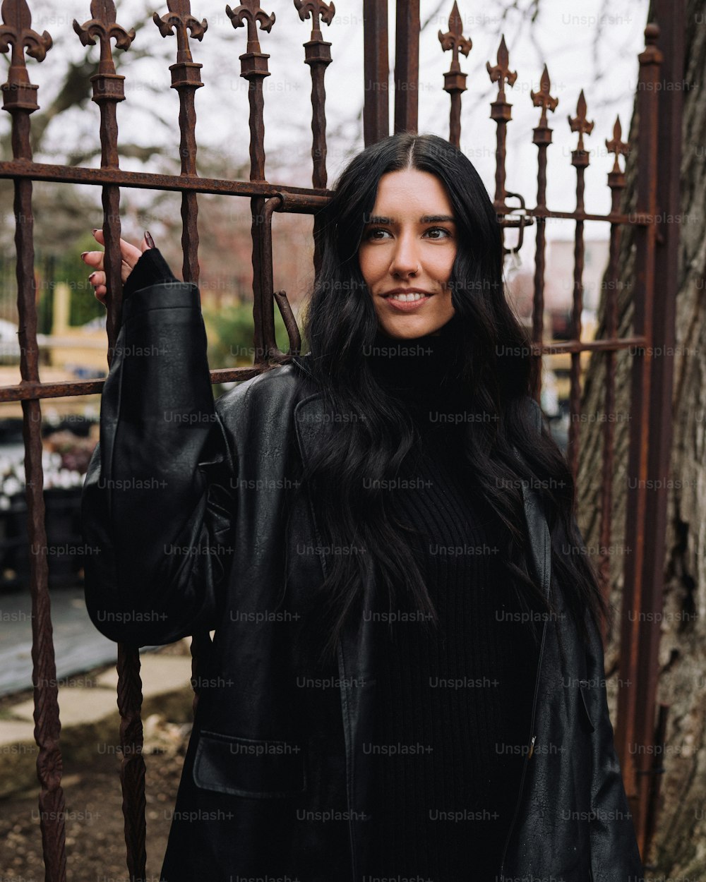 a woman standing in front of a metal fence