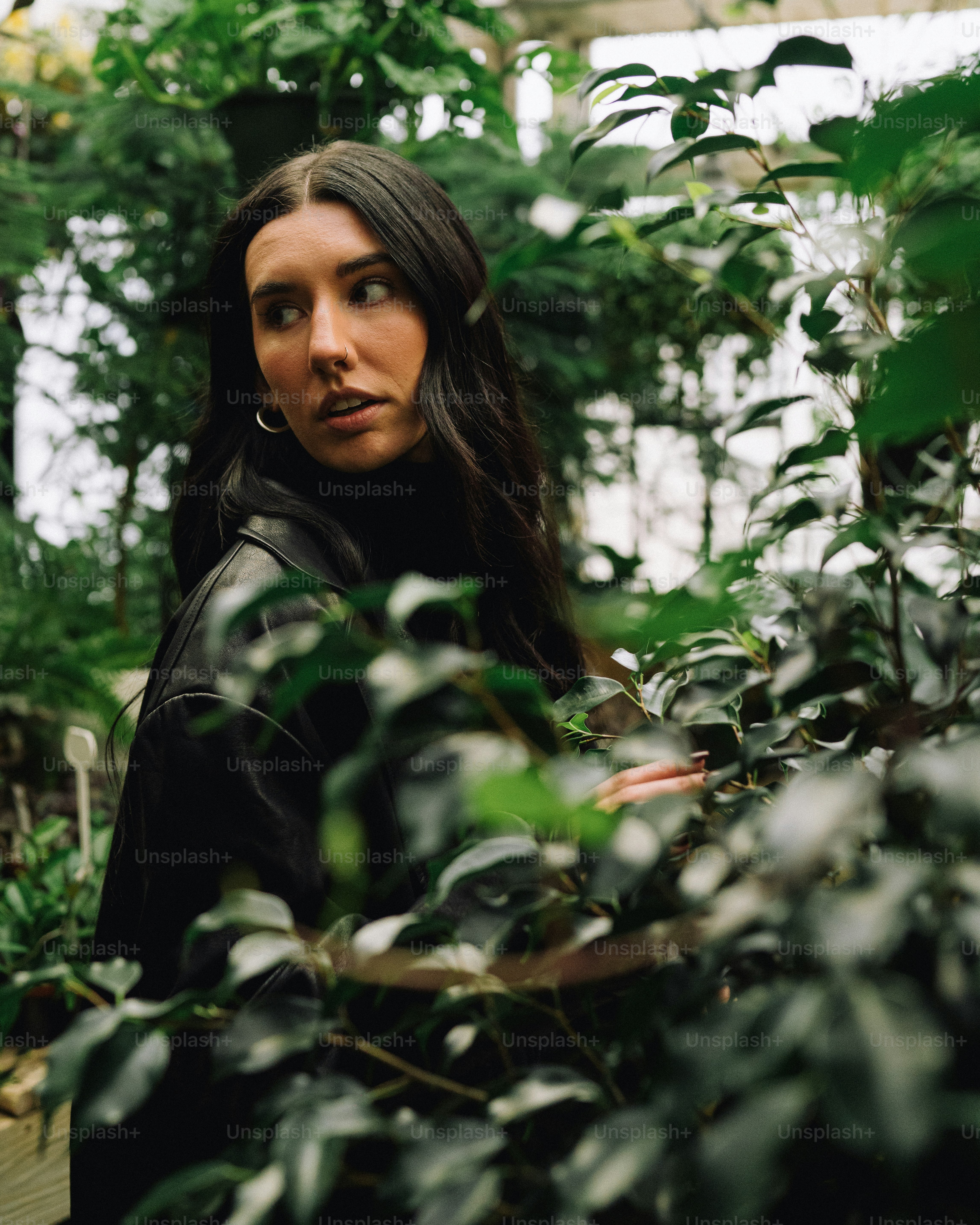 a woman standing in a greenhouse surrounded by plants