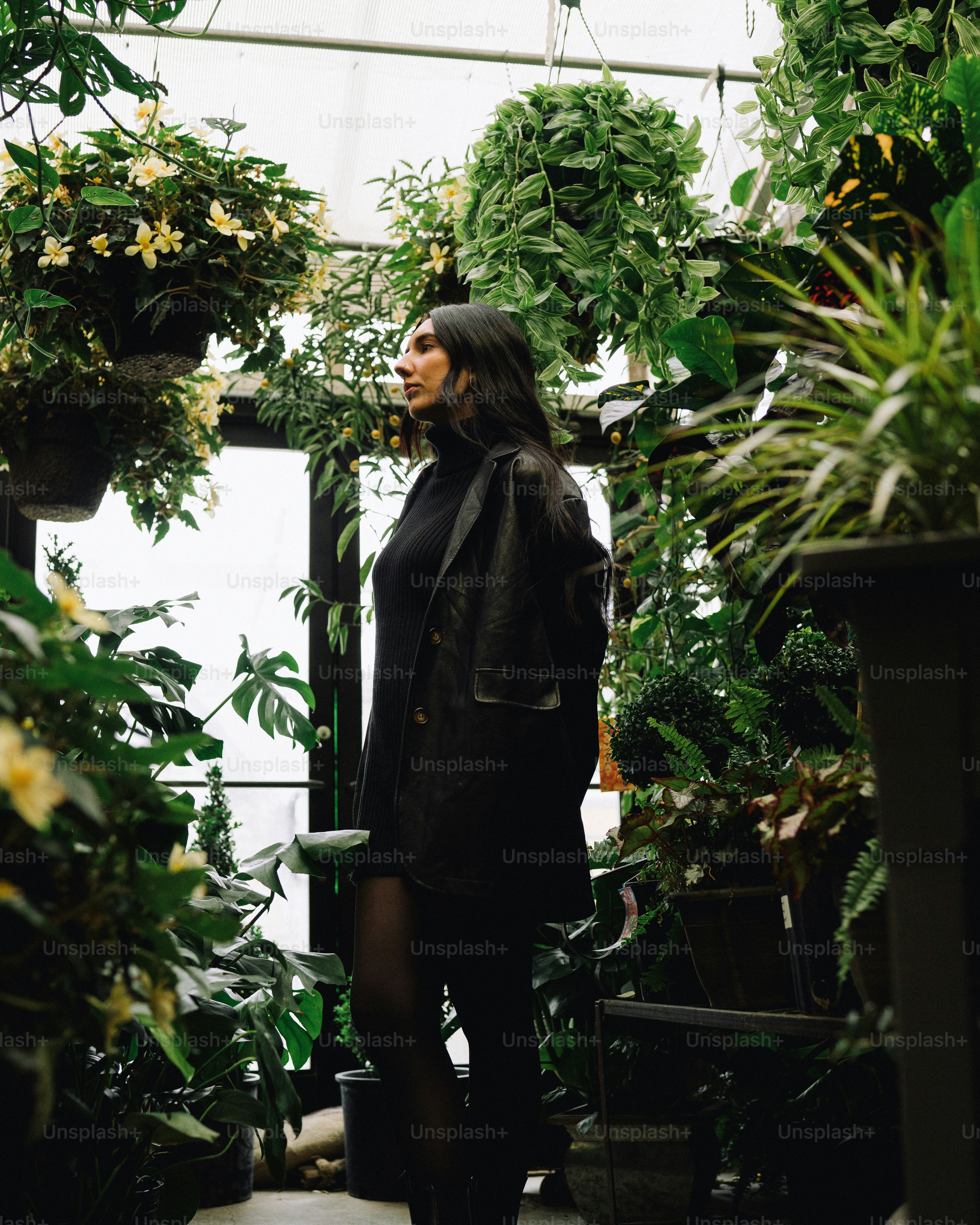 a woman standing in a greenhouse surrounded by plants