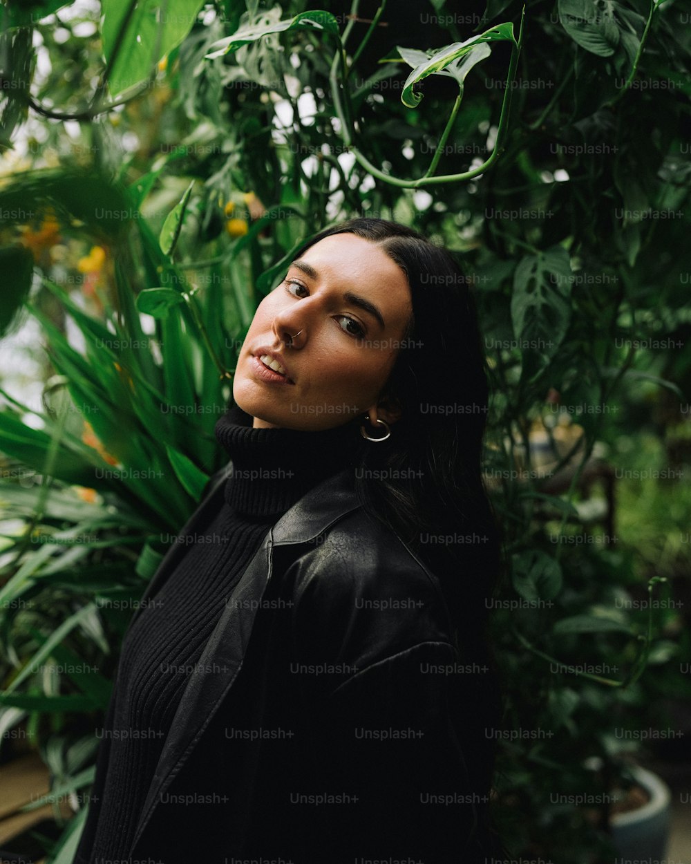 a woman standing in front of a green plant