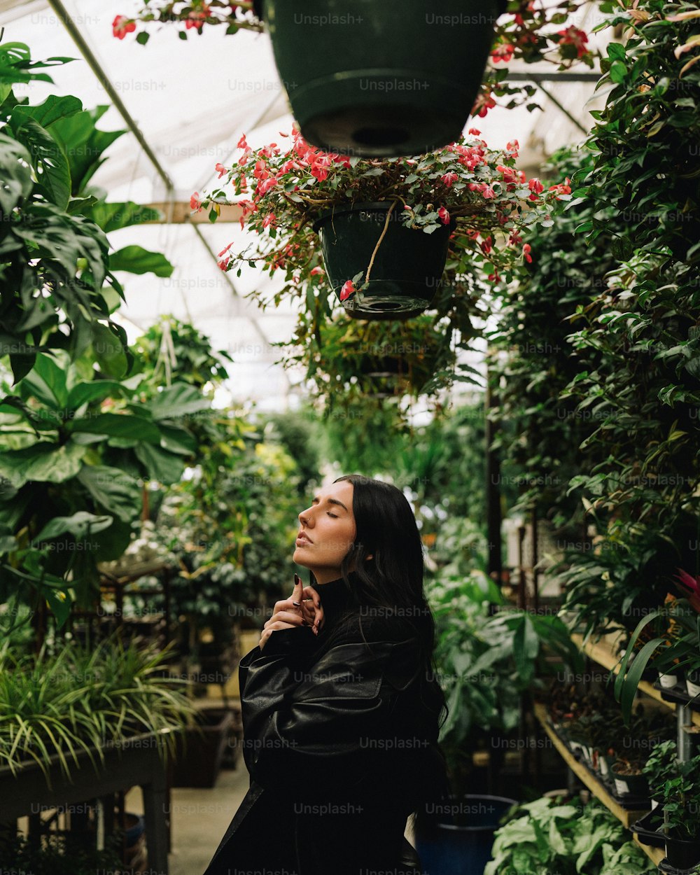 a woman standing in a greenhouse looking up