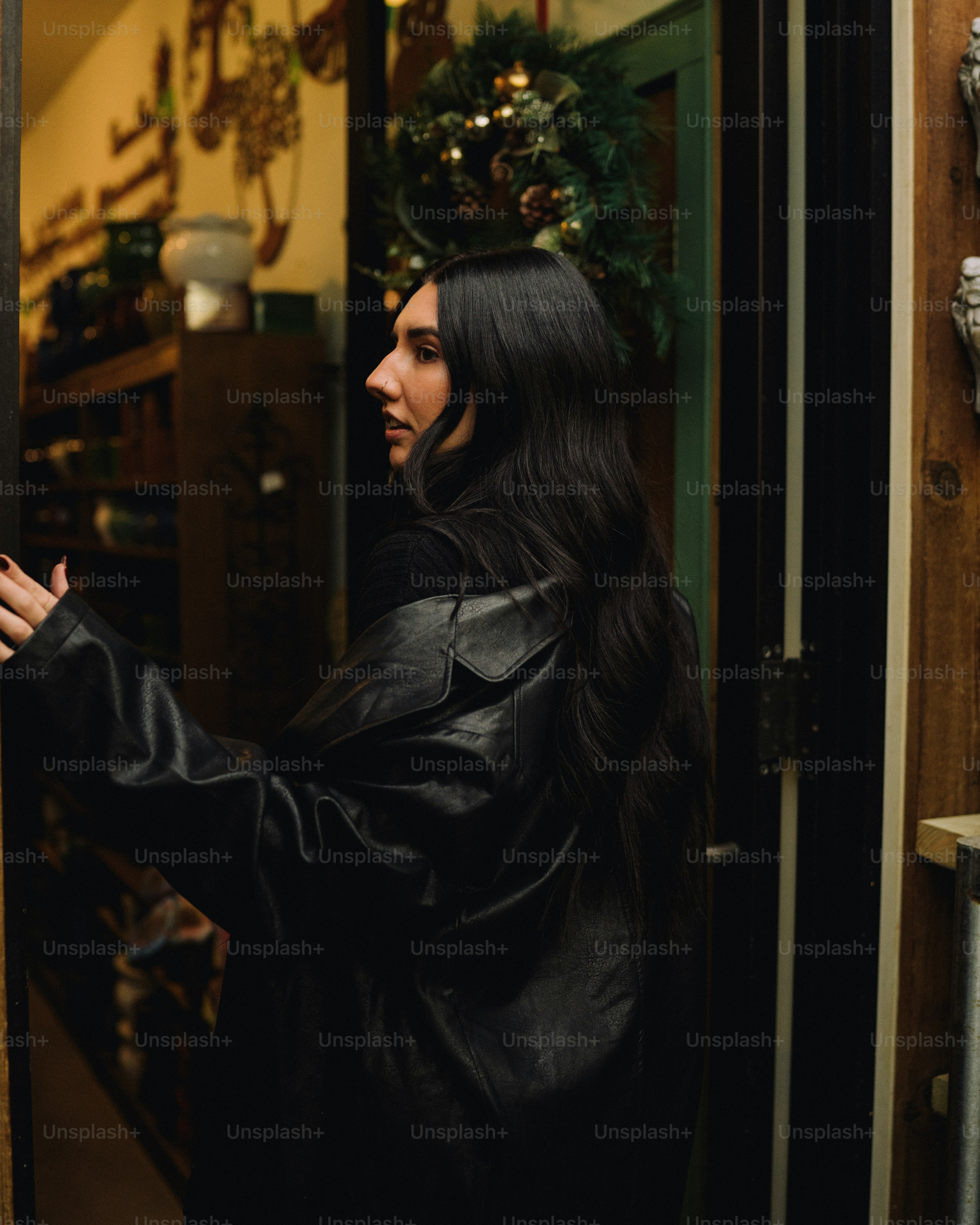 a woman in a black leather jacket is opening a door