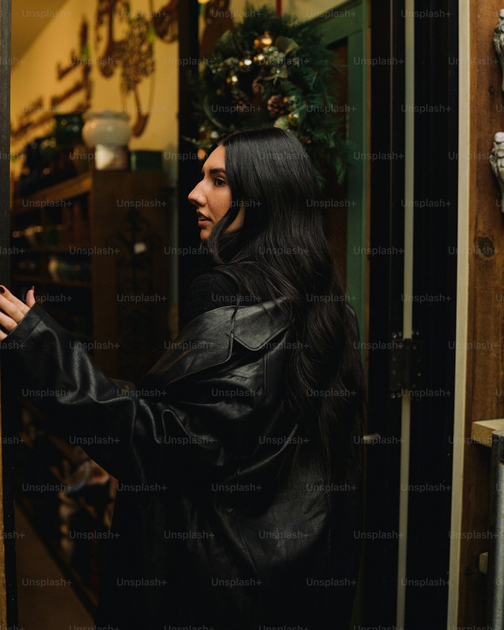 a woman in a black leather jacket is opening a door