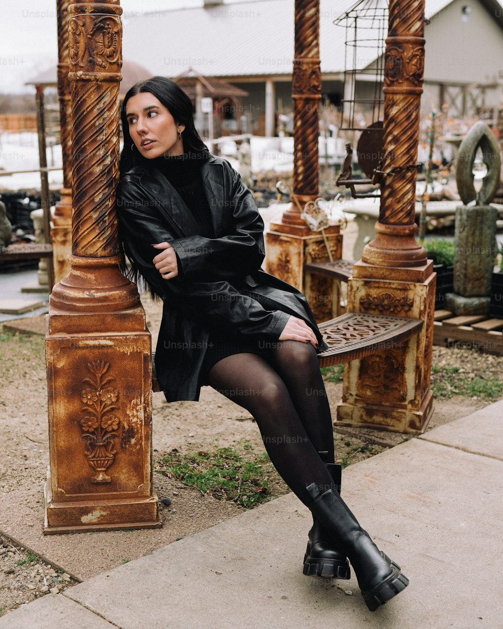 a woman sitting on a bench in a black dress