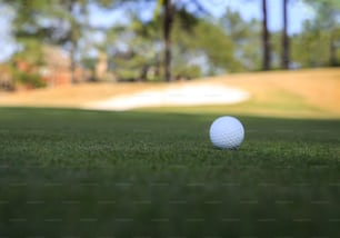 Ein weißer Golfball, der auf einer grünen Wiese sitzt