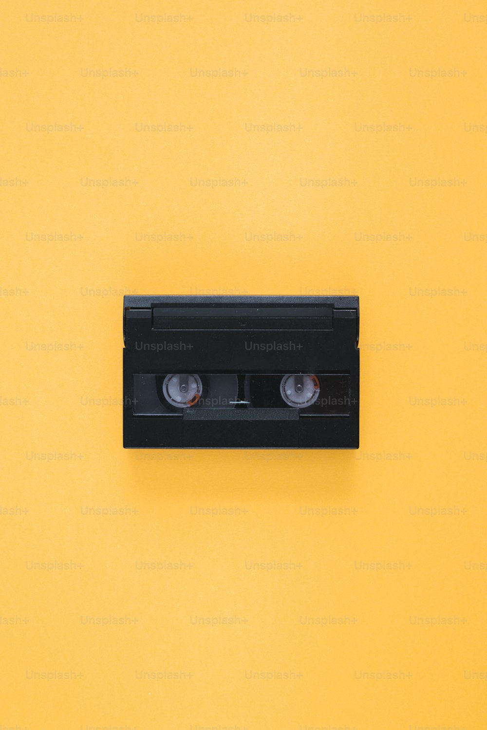 a couple of black cassettes sitting on top of a yellow wall