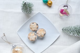 a white plate topped with muffins next to a christmas tree