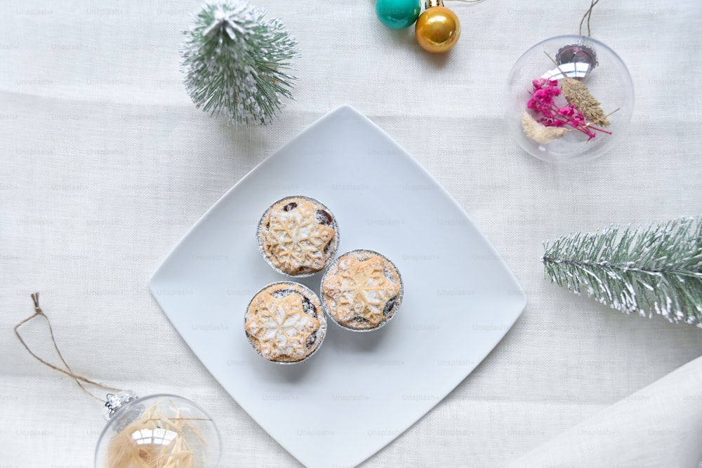 Une assiette blanche surmontée de muffins à côté d’un sapin de Noël