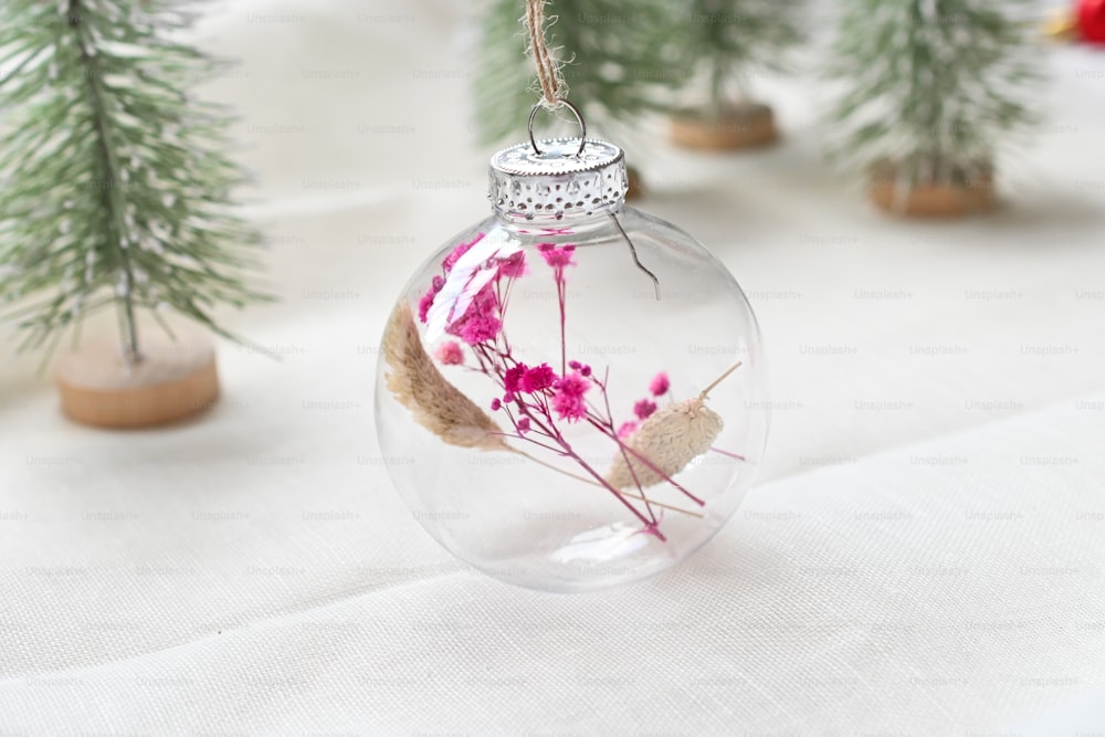 a glass ornament with pink flowers inside of it