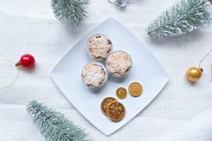 Un plato blanco cubierto con cupcakes junto a decoraciones navideñas