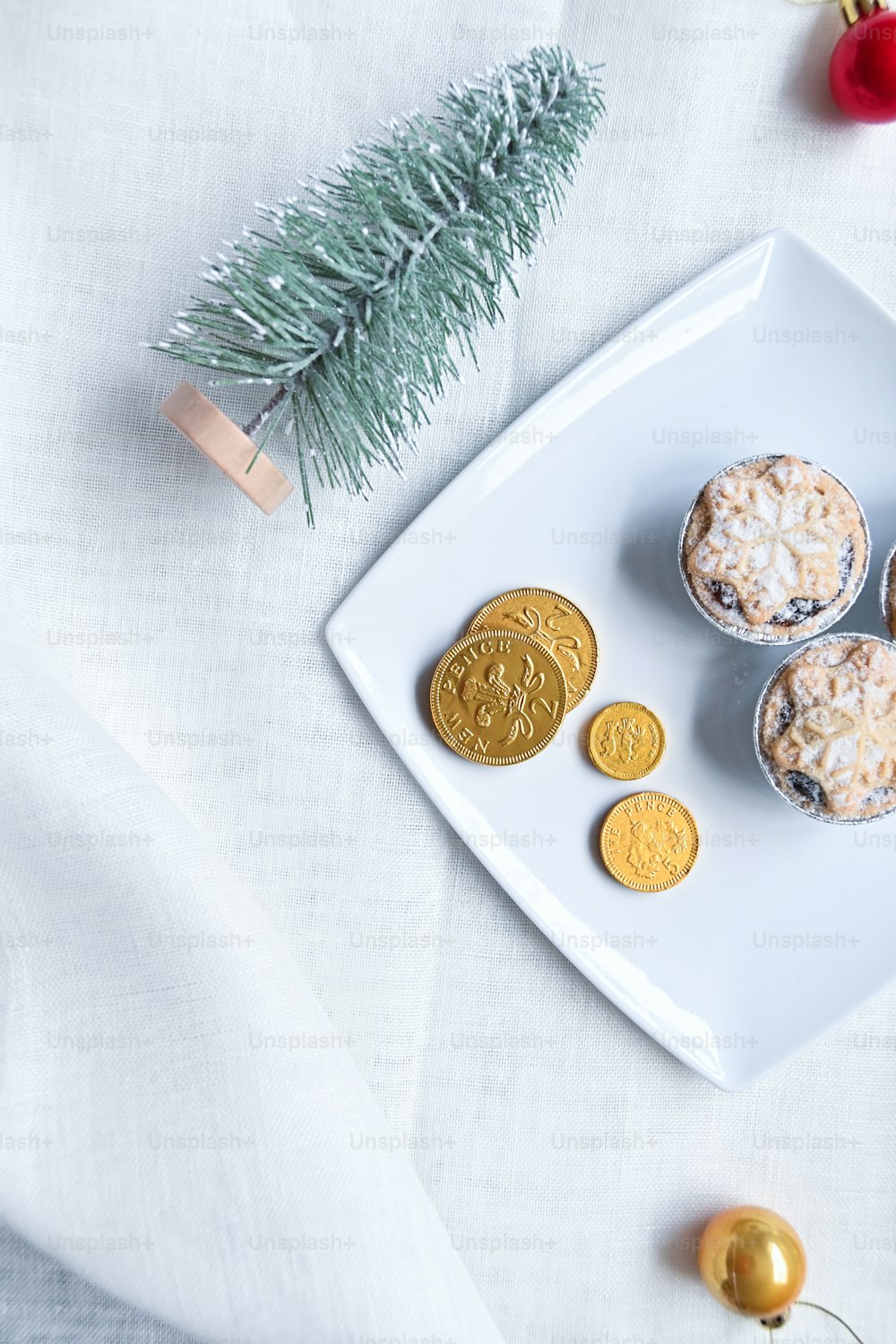 Une assiette blanche garnie de biscuits à côté d’un sapin de Noël