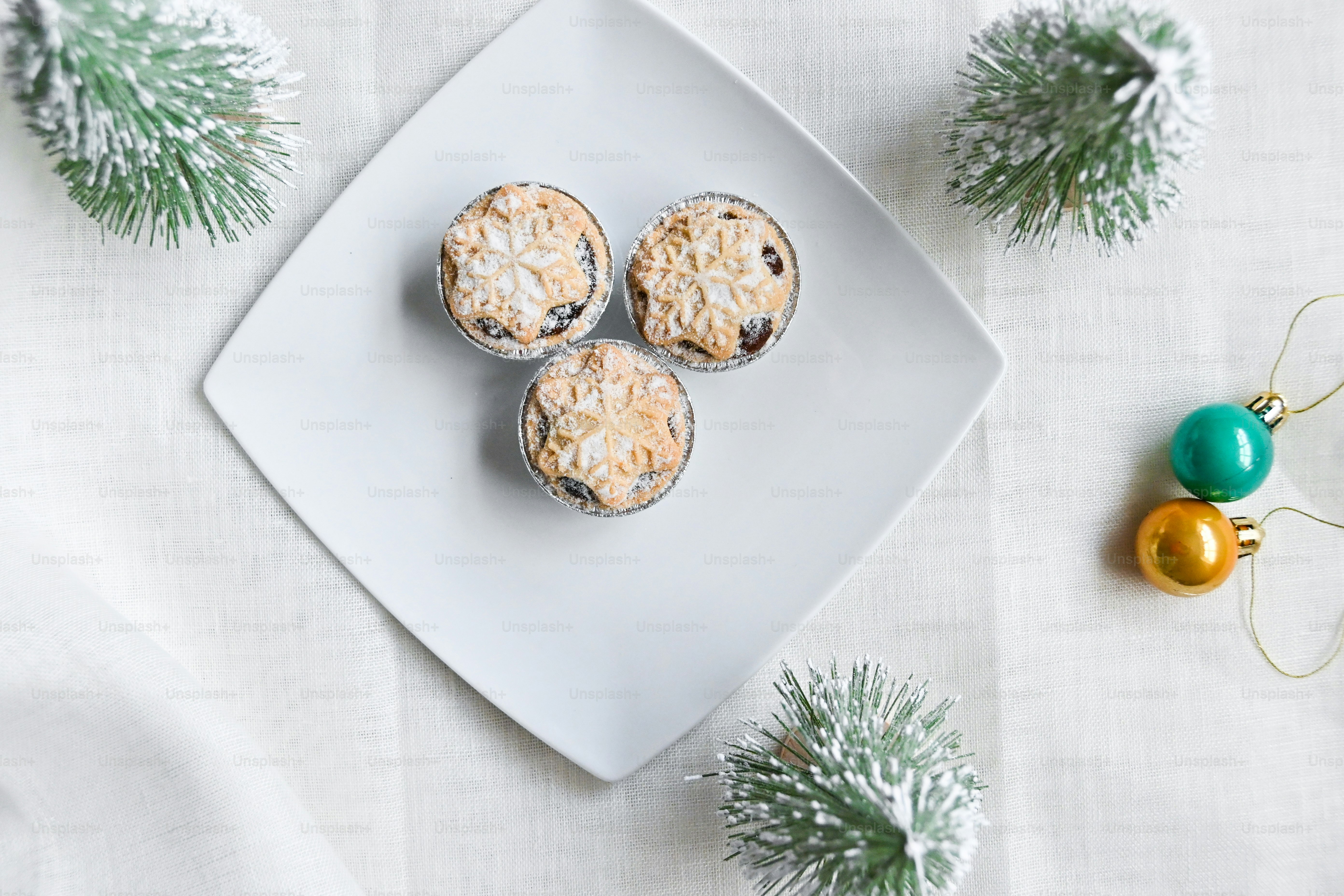 Un piatto bianco sormontato da tre muffin accanto a un ornamento natalizio