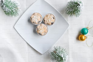 a white plate topped with three muffins next to a christmas ornament