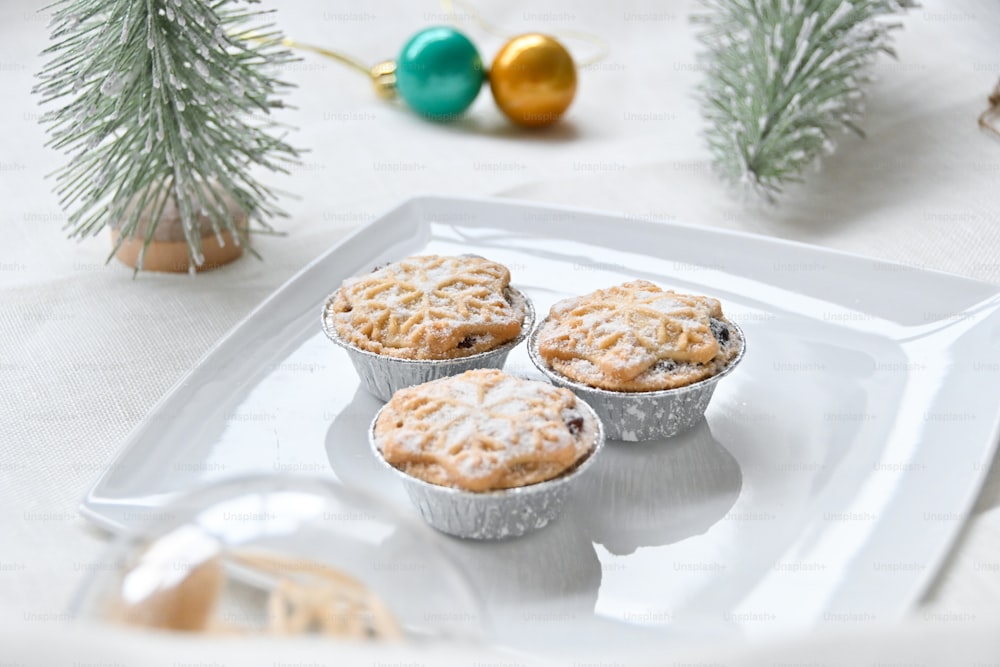 three muffins sitting on a white tray next to a christmas tree