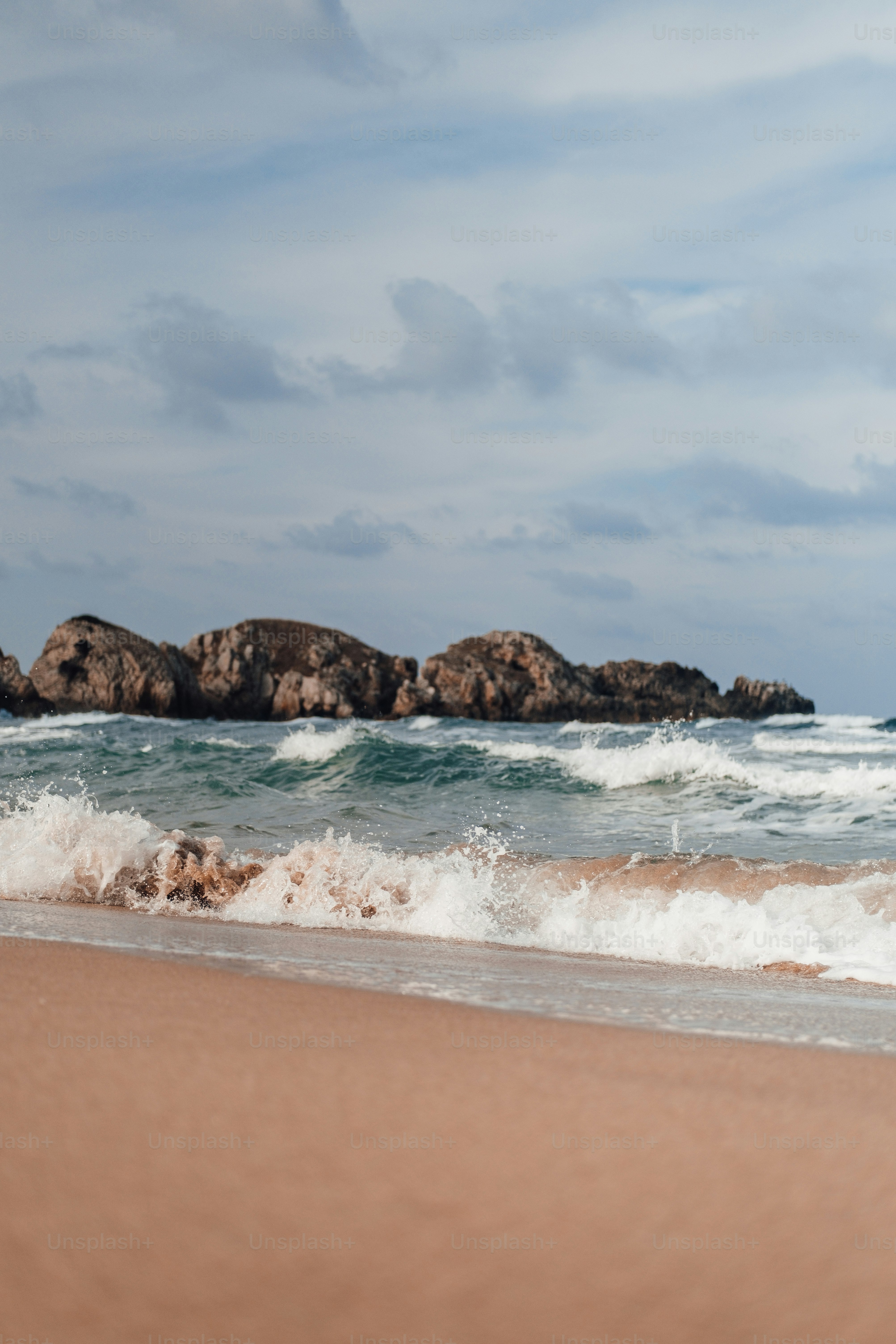 a sandy beach with waves coming in to shore