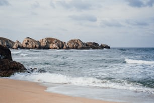 um afloramento rochoso no oceano ao lado de uma praia de areia