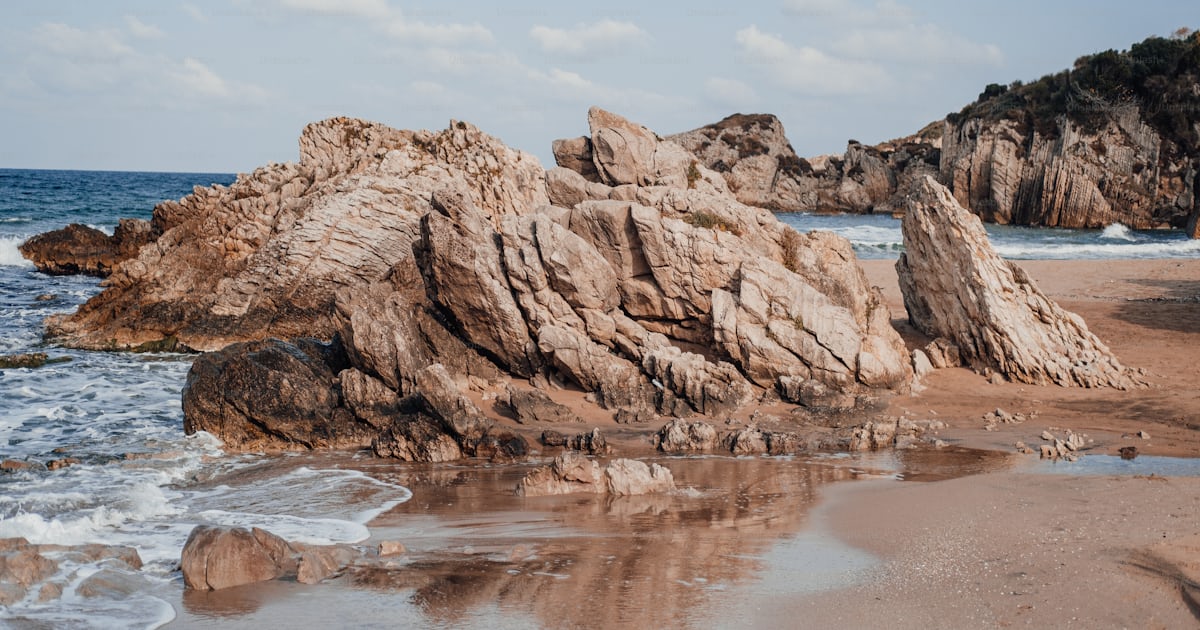 Une formation rocheuse sur une plage avec des vagues qui arrivent photo ...