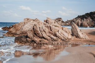 a rock formation on a beach with waves coming in