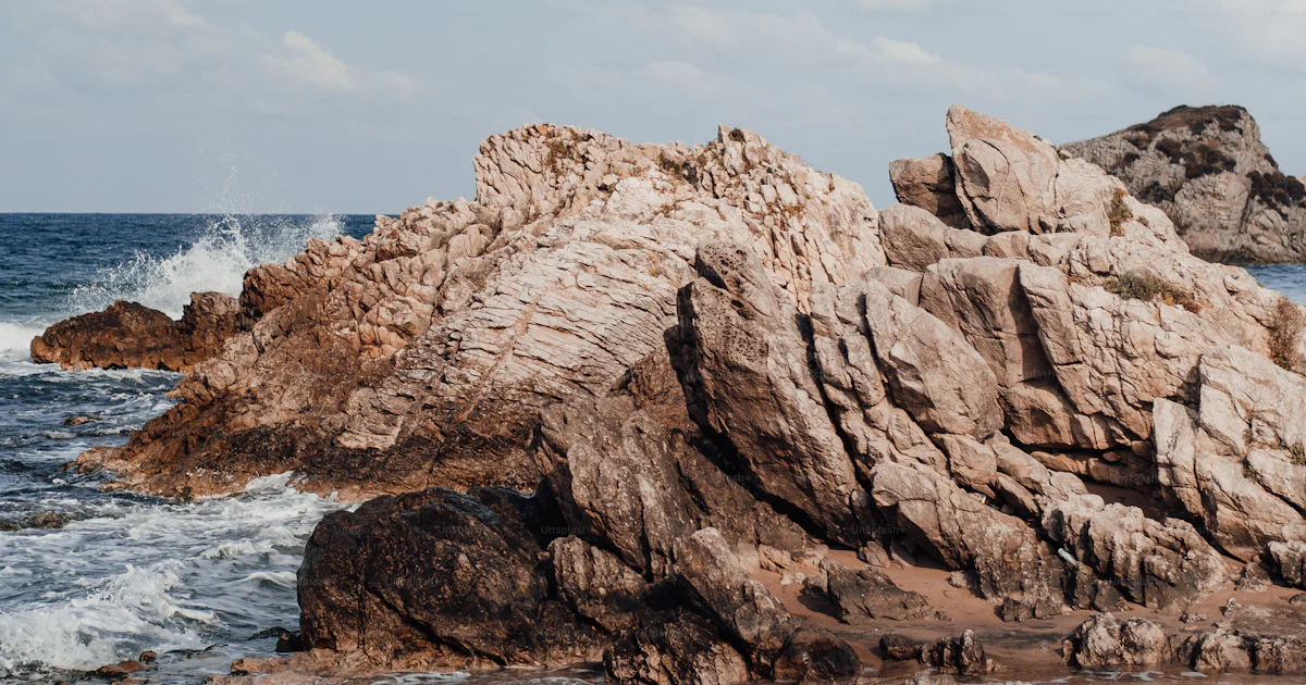 Oceanfront Rocks A rock formation on the beach near the ocean photo – Coastal Image on ...