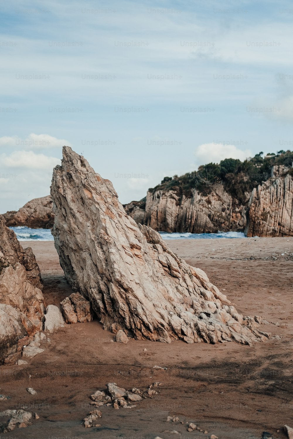 una grande roccia seduta sulla cima di una spiaggia sabbiosa