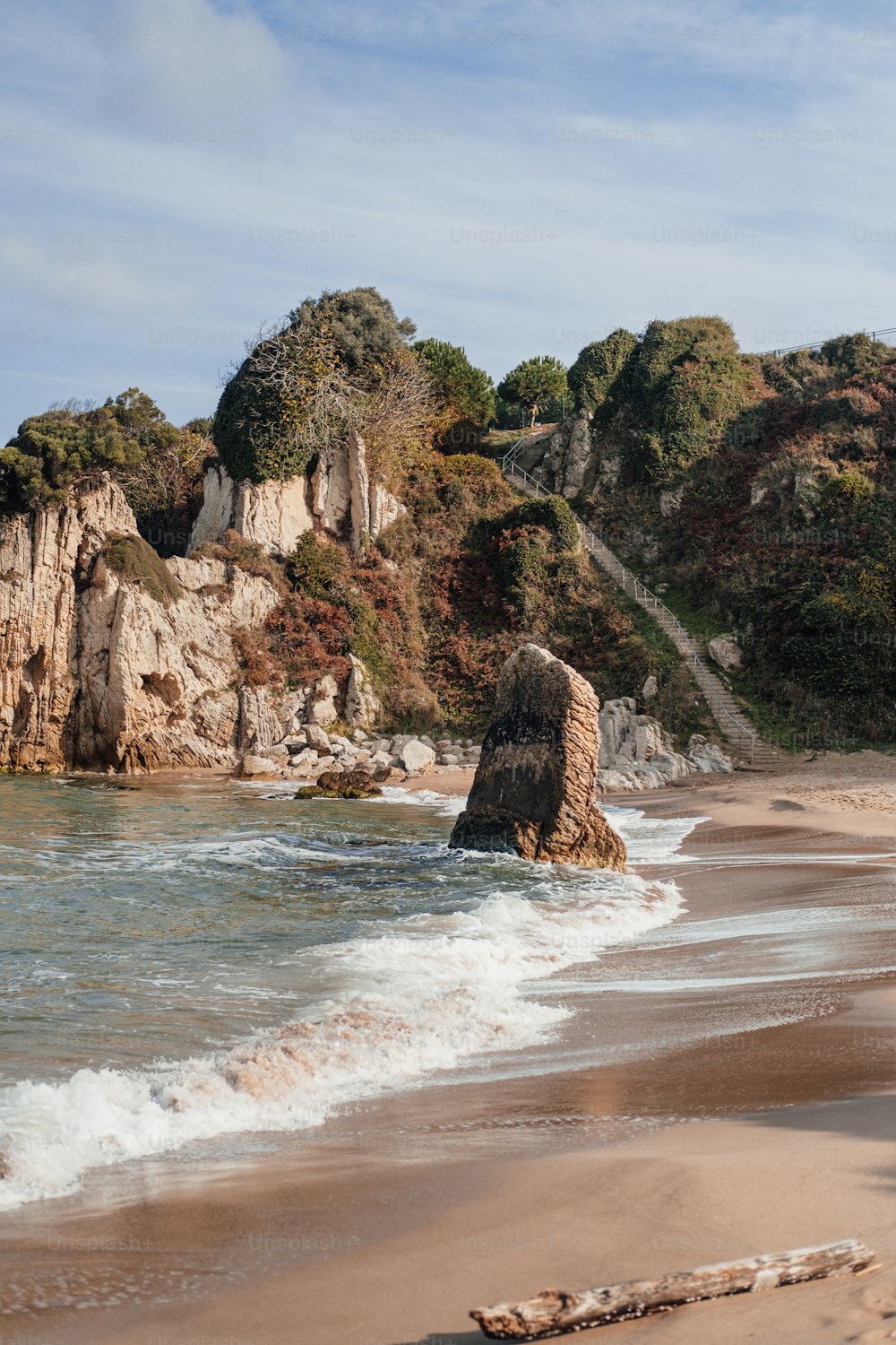 uma praia de areia ao lado de um penhasco rochoso