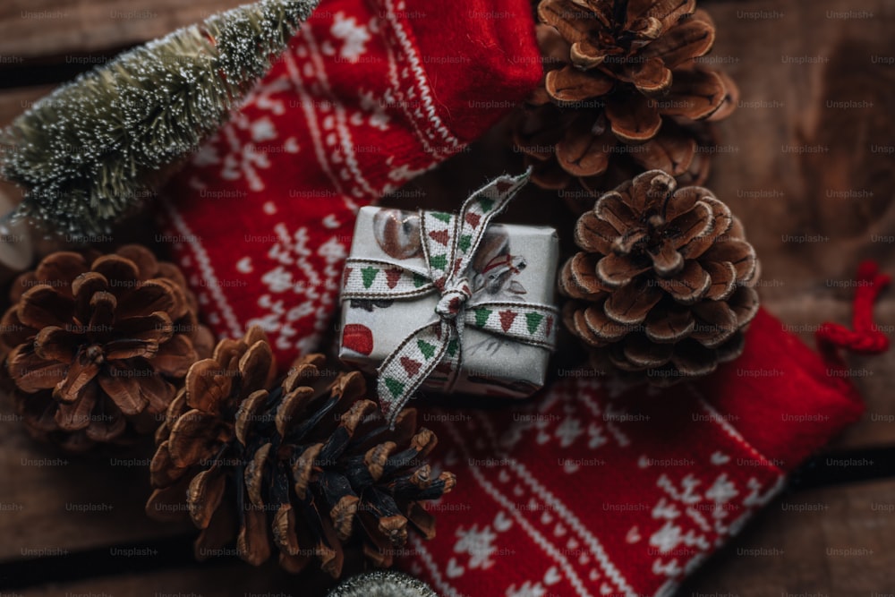 Ein Weihnachtsgeschenk, eingewickelt in ein rot-weißes Band neben Tannenzapfen