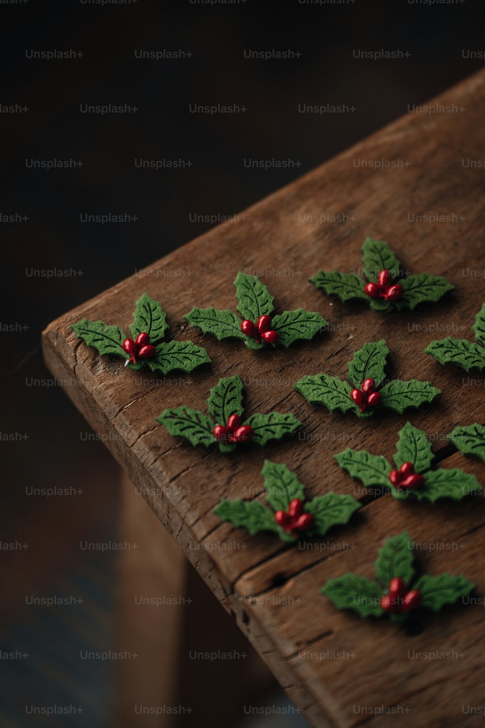 a wooden table topped with holly leaves and red berries