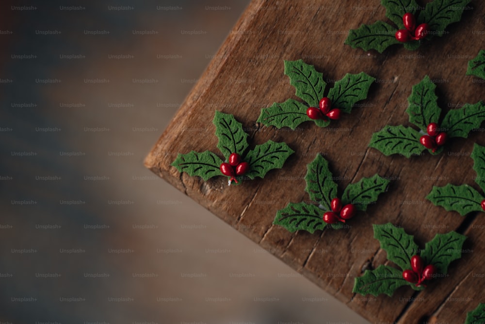 a wooden table topped with holly and red berries