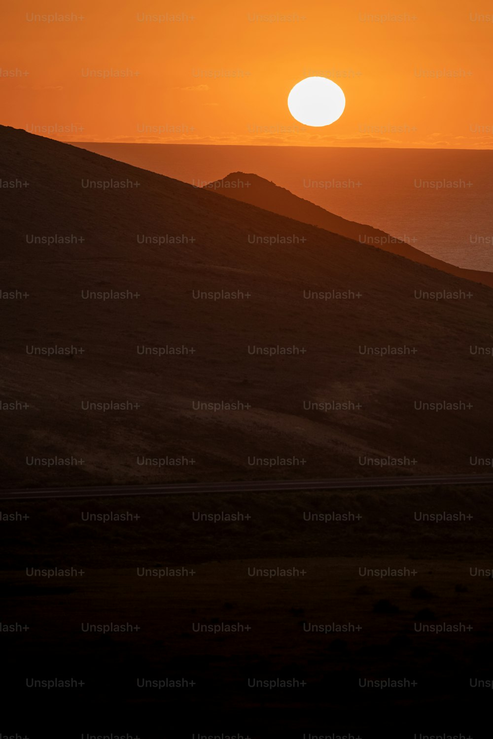 the sun is setting over a hill in the desert